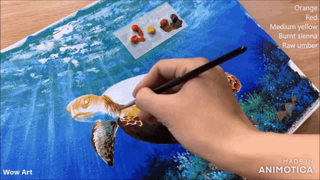 a person is painting a sea turtle with orange red and medium yellow paint