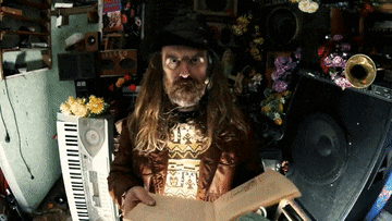 a man with long hair and a beard is holding a book in his hands