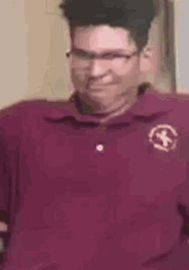a man wearing glasses and a maroon shirt is smiling and looking at the camera .