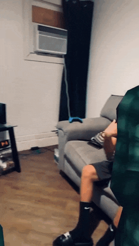 a person sitting on a couch in a living room with a remote control