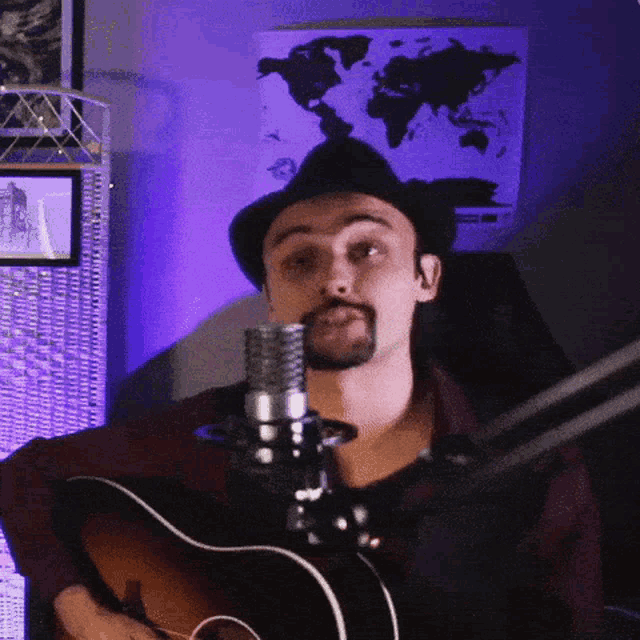 a man playing a guitar in front of a microphone with a map of the world in the background