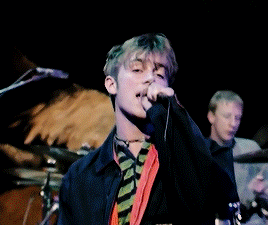 a man singing into a microphone with a blurred background