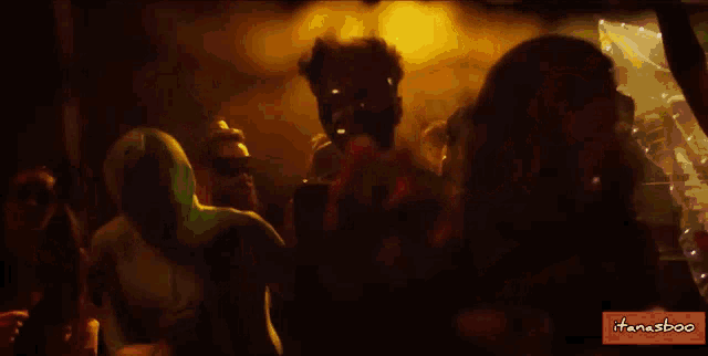 a group of people are dancing in a dark room with a red banner that says ifansboo