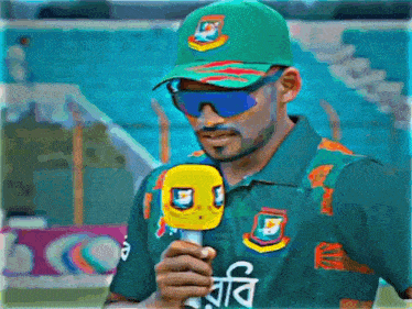 a man wearing sunglasses and a green hat holds a microphone
