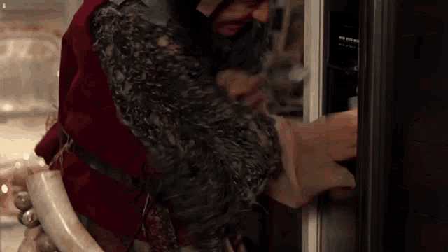 a man in a red vest is opening a fridge door