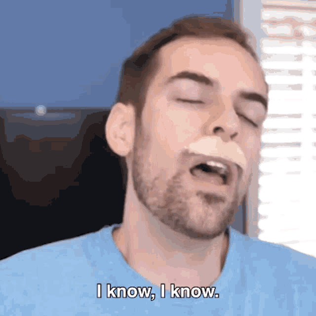 a man with a beard is eating a chip and says i know i know .