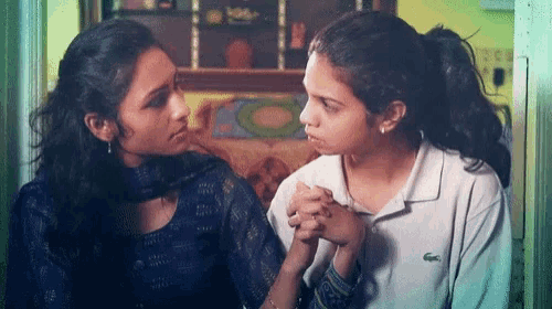 a woman wearing a white lacoste shirt is holding another woman 's hand