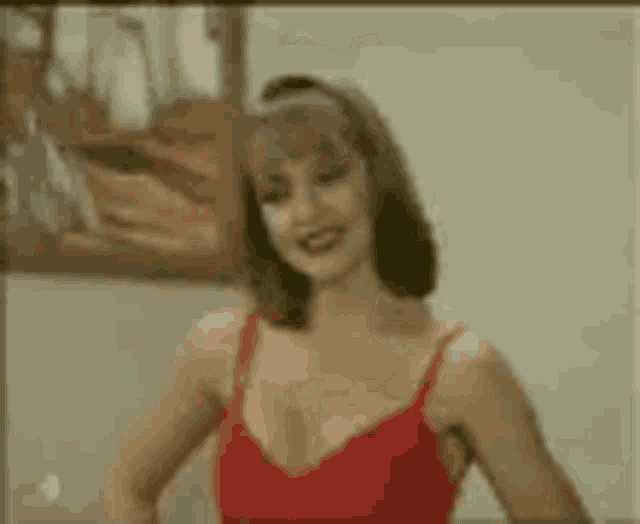 a woman in a red bra is standing in front of a mirror with her hair in a hat .