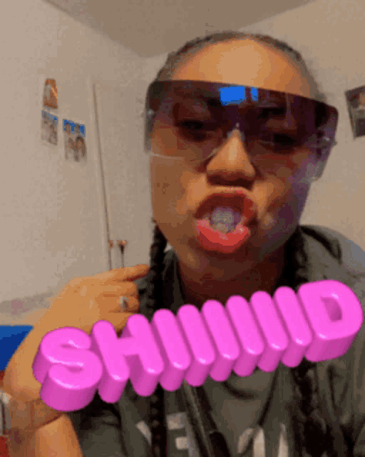 a woman wearing sunglasses and holding a pink sign that says siiiiid