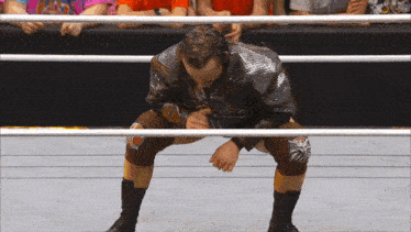 a wrestler kneeling down in a ring with a crowd behind him