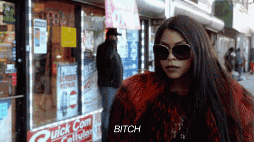 a woman wearing sunglasses and a red fur coat is standing in front of a store that says quick com cellular .