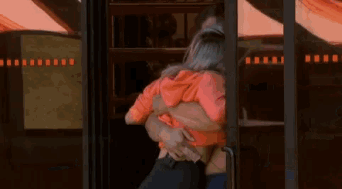 a man and a woman are hugging each other while standing in a doorway .