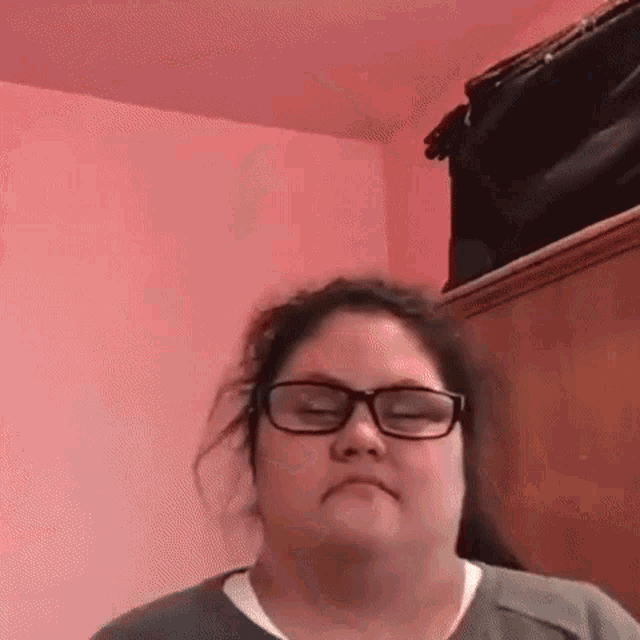 a woman wearing glasses is making a funny face in a room .