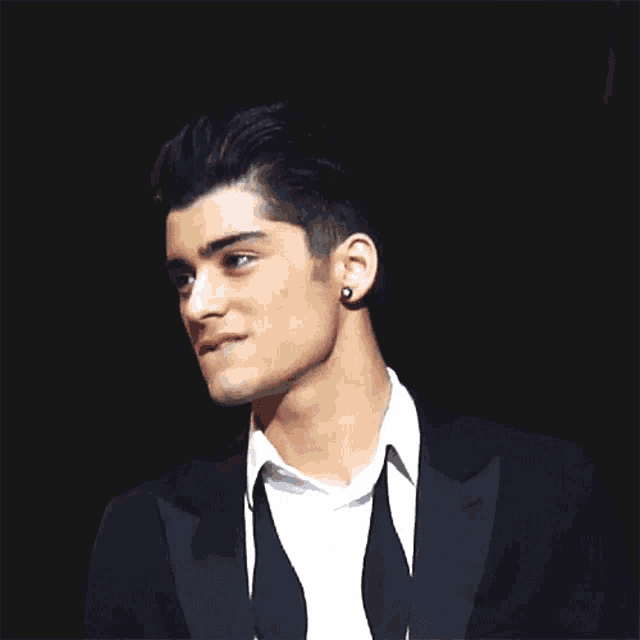 a close up of a man wearing a suit and tie with a black background