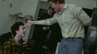 a man with a tattoo on his arm is reaching out to touch another man 's face
