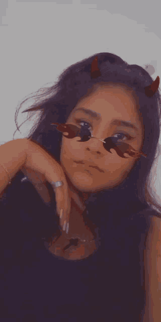 a girl wearing sunglasses with flames on them and horns on her head .