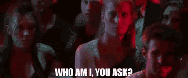 a man with long hair is holding a microphone and saying `` who am i , you ask '' .