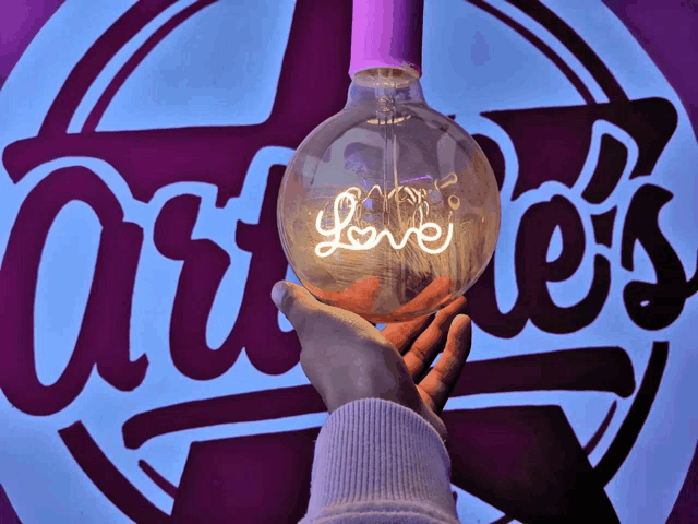 a hand holding a light bulb that says love