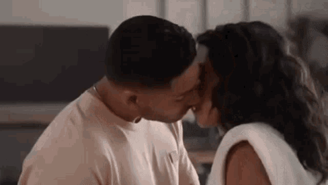 a man and a woman are kissing in the living room .