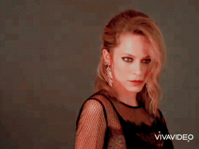 a woman in a black dress is standing in front of a camera with the words vivavideo on the bottom