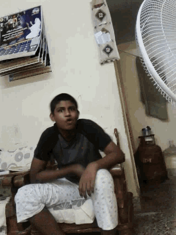 a man sits on a bed in front of a fan that says tct