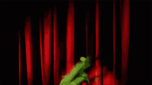 kermit the frog is dancing in front of a red curtain