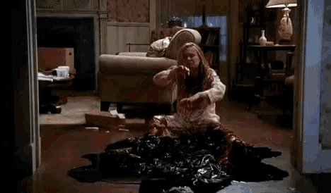 a woman is sitting on the floor in a living room with the word fuck on the floor .