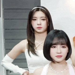 two girls are standing next to each other in a room .