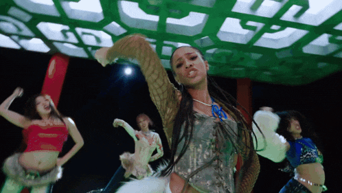 a group of women are dancing in front of a green light