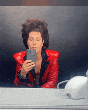 a man in a red leather jacket is taking a picture of himself in a mirror
