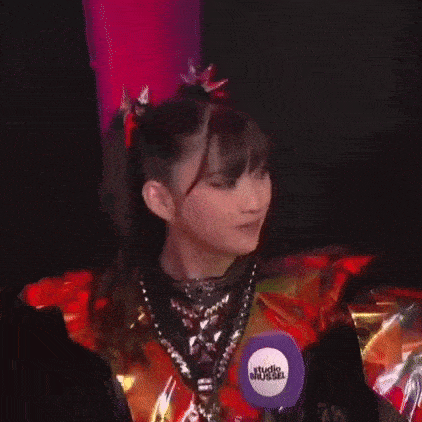 a woman in a red and gold outfit is smiling and wearing a microphone .