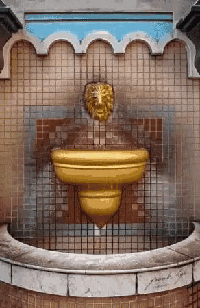 a yellow fountain with a lion head on it