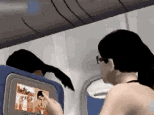 a woman is sitting on an airplane using a touchscreen .