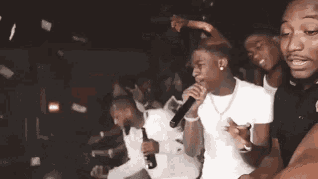 a man is singing into a microphone while money is falling from the ceiling .