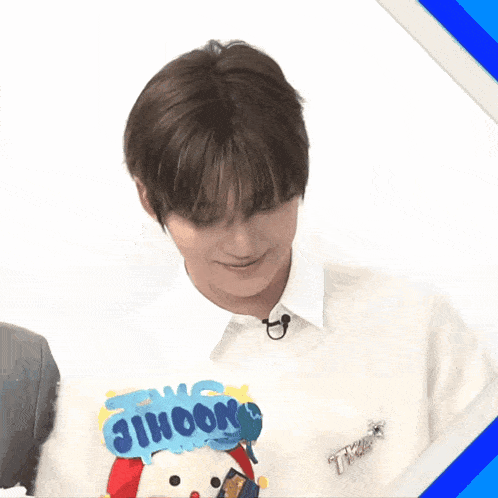 a young man is holding a stuffed animal with a sign that says jihoon