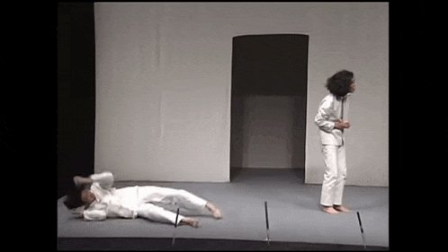 a man is laying on the floor on a stage while a woman stands next to him .