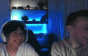 two people wearing headphones are smiling in front of a blue lighted wall