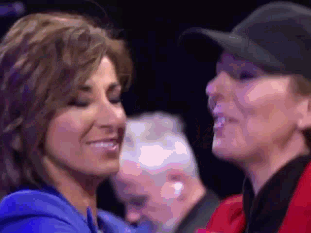 two women are looking at each other and smiling in a dark room
