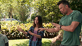 a man in a green shirt is standing next to a woman in a plaid shirt .