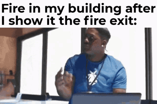 a man in a blue shirt is sitting in front of a laptop computer and talking about fire in his building .