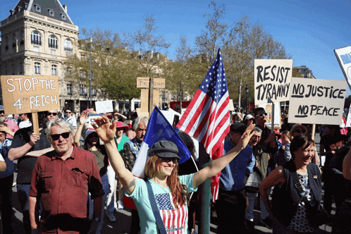 a protester holds a sign that says resist tyranny no justice no peace