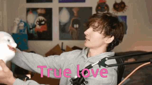 a man is holding a stuffed animal in front of a microphone with the words true love written on the bottom