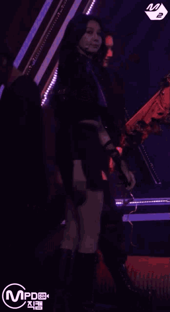 two women are dancing on a stage with purple lights and the word mpd on the bottom