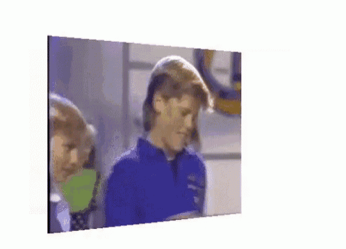 a woman in a blue shirt is looking at herself in the mirror
