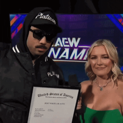 a man and a woman are posing for a picture in front of a screen that says aew nam