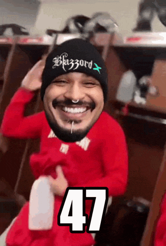 a man wearing a black beanie and a red shirt has the number 47 on his chest