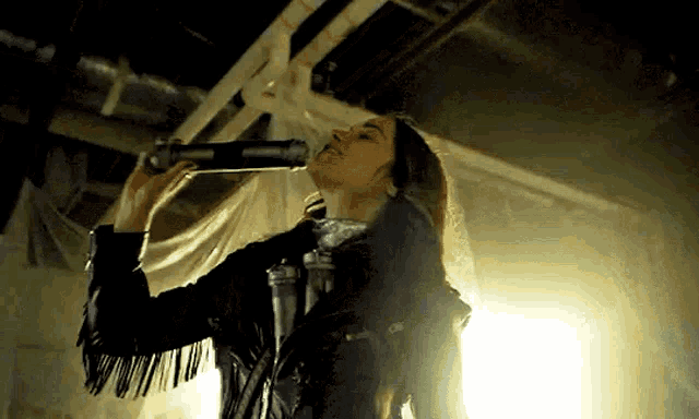a woman in a leather jacket is looking through a telescope in a dark room .