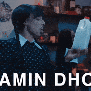 a man in a black dress is holding a bottle of milk with the words amin dhc written below him