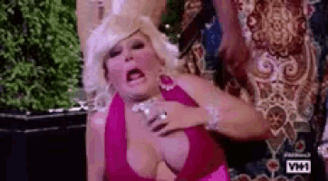 a woman in a pink dress is being held by a man in a wig .