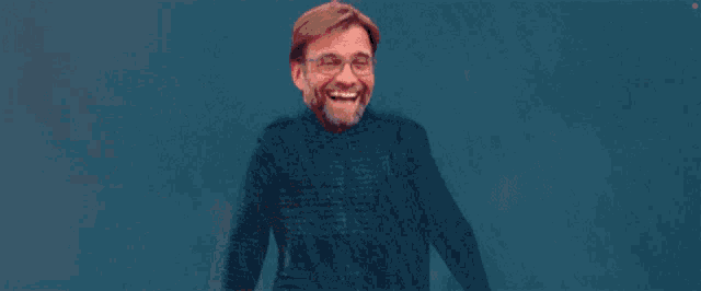 a man with glasses and a beard is smiling and holding up a red light